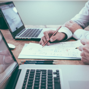 Deux personnes collaborent sur un projet devant des ordinateurs. - Agence web Prism'