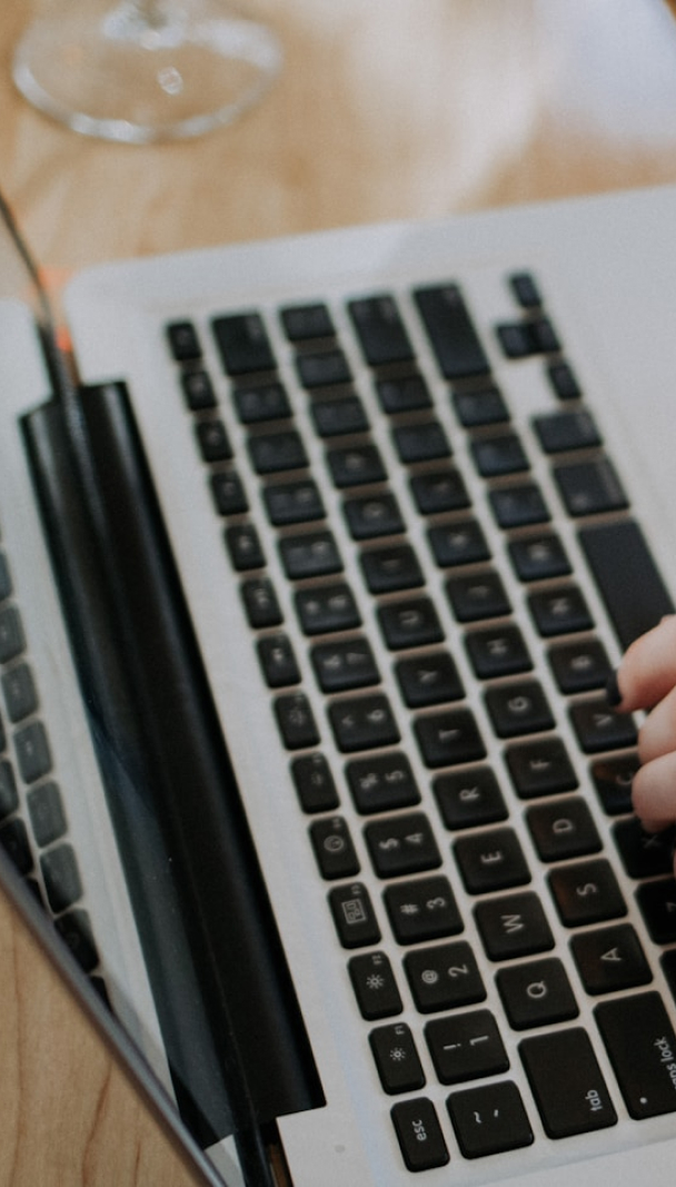 Main sur un clavier d'ordinateur portable, verre en arrière-plan.