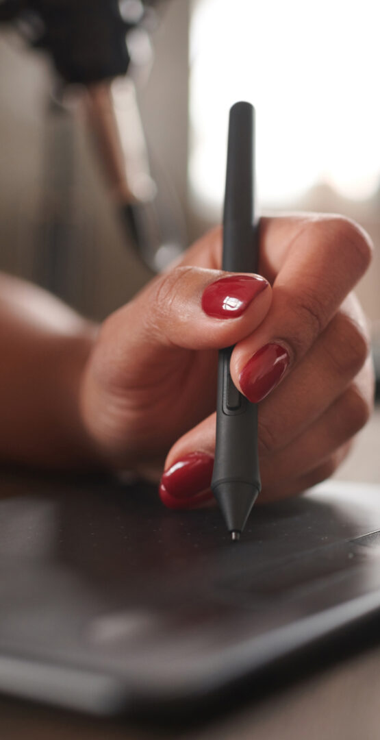 Une main utilise un stylet sur une tablette graphique. - Agence web Prism'