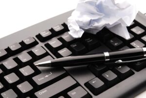 Crumble de papier et stylo sur un clavier d'ordinateur.