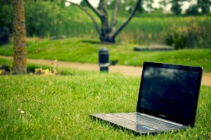 Un ordinateur portable est posé sur l'herbe dans un parc.